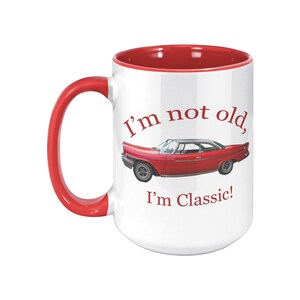 White ceramic mug with vintage 1962 Chrysler 300 photo and 'I'm not old, I'm classic!' quote. Reverse shows '1962 Chrysler 300' text. Options: black, blue, pink, or red handle/interior.