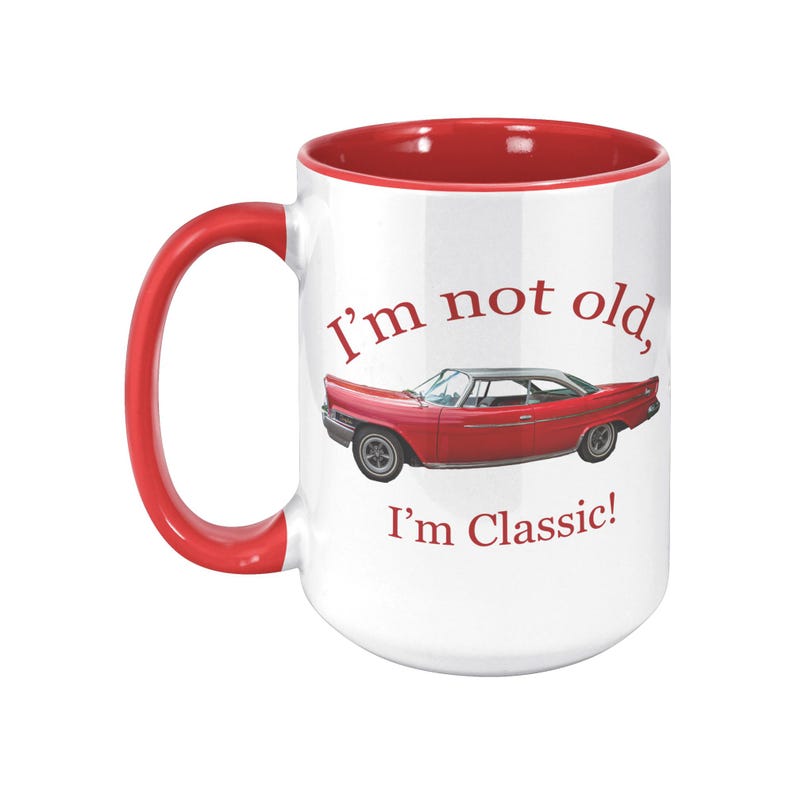 White ceramic mug with vintage 1962 Chrysler 300 photo and 'I'm not old, I'm classic!' quote. Reverse shows '1962 Chrysler 300' text. Options: black, blue, pink, or red handle/interior.