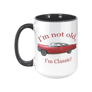 White ceramic mug with vintage 1962 Chrysler 300 photo and 'I'm not old, I'm classic!' quote. Reverse shows '1962 Chrysler 300' text. Options: black, blue, pink, or red handle/interior.