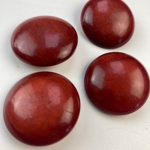 Op de afbeelding: Vier ronde, rode, glanzende knopen. De knopen zijn glad en hebben een lichte glans.