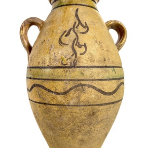 Puede incluir: Un jarrón grande de cerámica amarilla con dos asas. El jarrón tiene un diseño pintado en marrón y verde con una línea ondulada y un patrón floral estilizado.