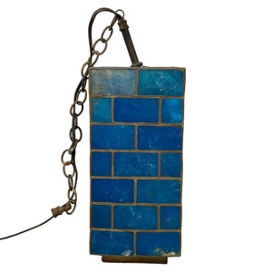 May include: A blue glass pendant light fixture with a chain and a metal frame. The glass is made up of small, rectangular pieces.