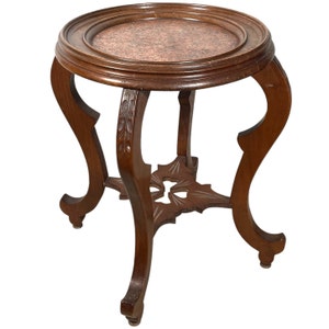May include: A dark brown wooden side table with a round copper top and intricate carved legs. The table has a unique design with a cross-shaped base.