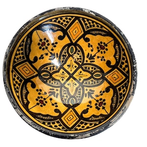 May include: A round ceramic bowl with a black rim and a yellow, black, and red geometric design.