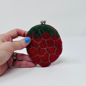 May include: A red and green beaded coin purse shaped like a strawberry.