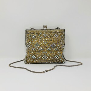 May include: A gold beaded evening bag with a silver chain strap and a clasp closure. The bag is decorated with iridescent rhinestones.