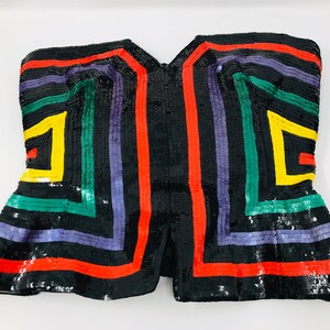 May include: A black sequined strapless top with a geometric pattern in red, yellow, green, and purple.