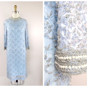 May include: A light blue beaded dress with a high neckline and long sleeves. The dress is adorned with pearl accents and a delicate floral pattern.
