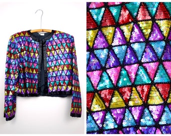 May include: A colourful sequined jacket with a geometric pattern of triangles in shades of pink, purple, blue, green, red, and yellow. The jacket has a black lining and long sleeves.