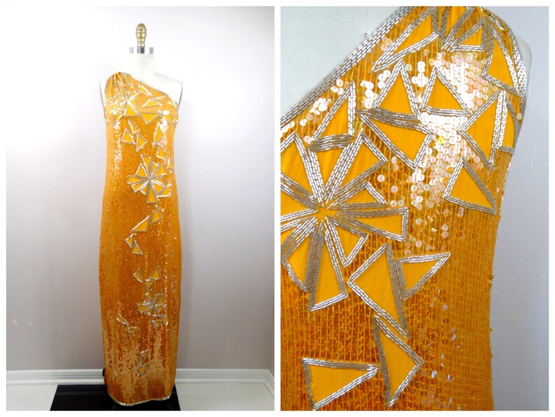 K&ouml;nnte beinhalten: Ein langes, einarmige Kleid in leuchtend gelber Farbe. Das Kleid ist mit Pailletten besetzt und hat ein geometrisches Muster aus silbernen Pailletten.
