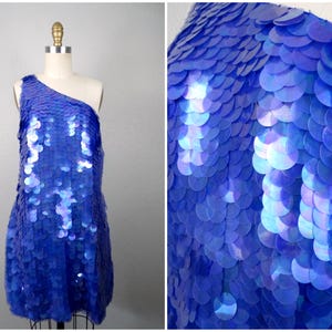 Peut inclure: Une robe à une épaule en sequins bleu irisés. Les sequins sont disposés en forme d'écailles.