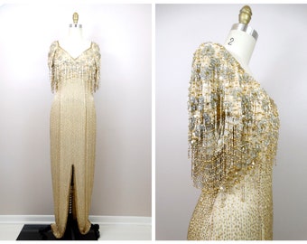 May include: A gold and silver beaded evening gown with a V-neckline and a long, flowing skirt. The gown has a beaded fringe detail on the bodice and sleeves.