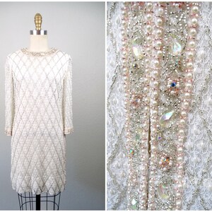 Puede incluir: Un vestido blanco de cuentas con un patrón de diamante y adornos de perlas y cristales.