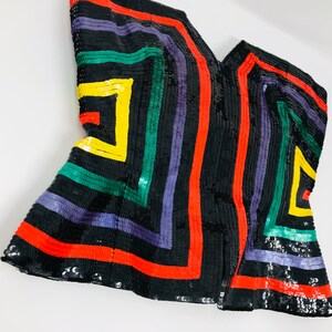 May include: A black sequined top with a geometric pattern in red, green, yellow, and purple.