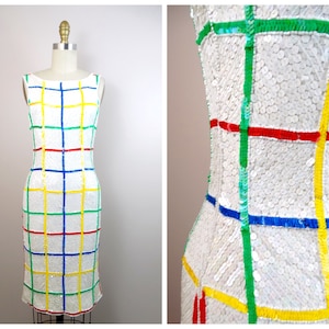 May include: A white sleeveless dress with a geometric pattern of colorful squares. The squares are outlined in red, blue, green, and yellow.