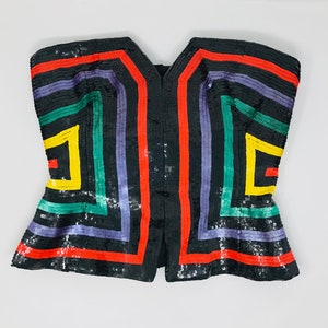 May include: A black sequined strapless top with a geometric pattern in red, yellow, green, and purple.