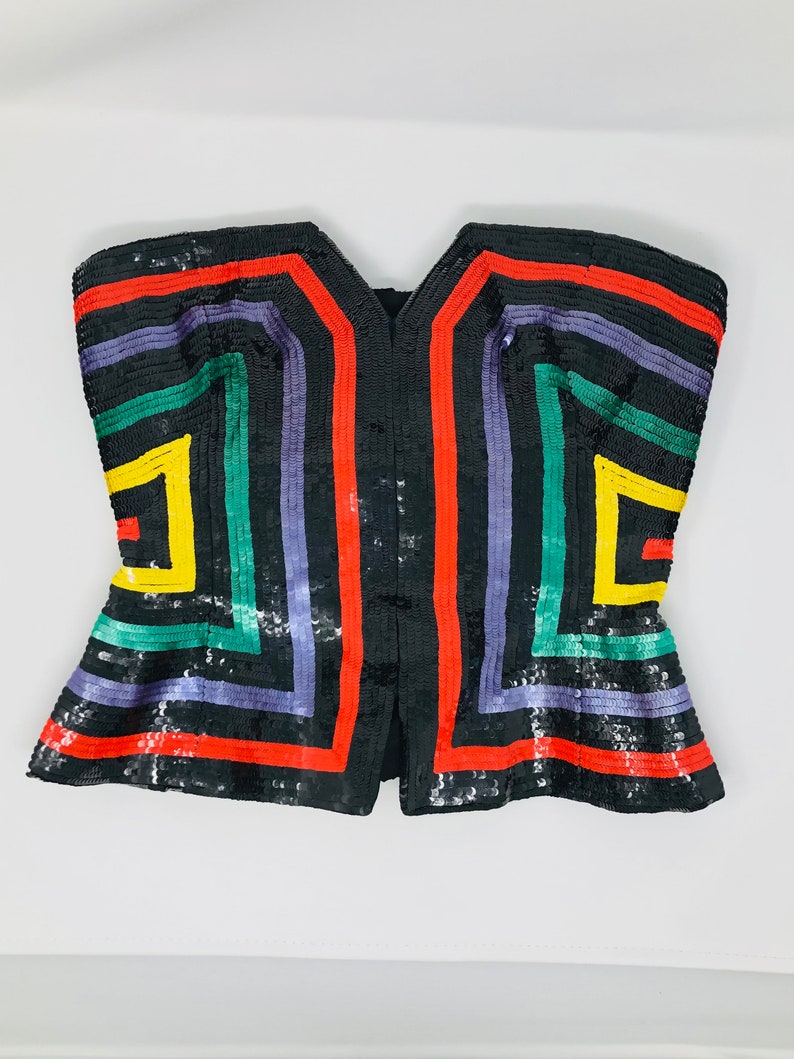 May include: A black sequined strapless top with a geometric pattern in red, yellow, green, and purple.