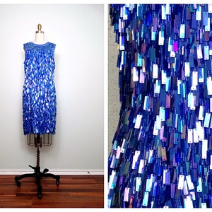 May include: A sleeveless blue dress with iridescent sequins. The sequins are arranged in a vertical pattern, creating a shimmering effect.