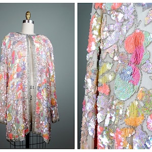 May include: A long, open-front jacket with a floral pattern made of iridescent sequins. The jacket is a light pink color with accents of orange, yellow, and green.