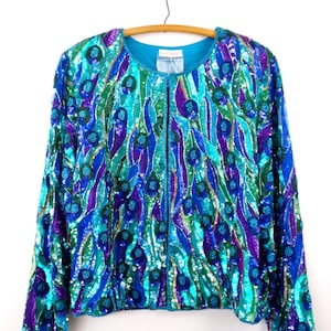 May include: A teal blue sequined jacket with a peacock feather design in shades of green, purple, and gold. The jacket has a zipper closure and long sleeves.
