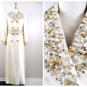 May include: A long white coat with a double breasted closure and a large embellished collar and cuffs. The embellishments are made of gold and silver beads, sequins, and rhinestones.