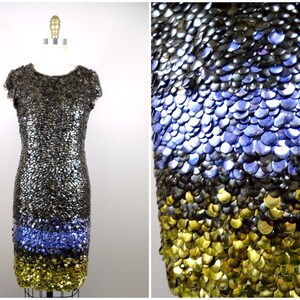 May include: A short, sleeveless dress made of silver, blue and gold sequins. The sequins are arranged in a graduated pattern, with the silver sequins at the top, the blue sequins in the middle and the gold sequins at the bottom.