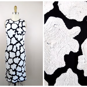 May include: A sleeveless black dress with a white abstract pattern. The pattern is made of small, round sequins.