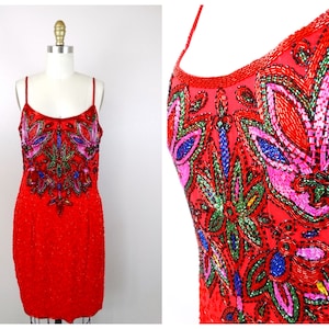 May include: A red sequined dress with a floral design embroidered with colorful beads. The dress has a sleeveless design and a fitted silhouette.