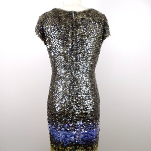 May include: A short-sleeved sequined dress with a gradient design. The top of the dress is a dark grey colour, transitioning to a light blue colour, and then to a gold colour at the bottom.