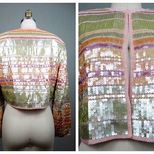 May include: A cropped sequined jacket with a pink, orange, and green striped pattern. The jacket has long sleeves and a pink trim.