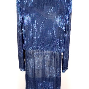 May include: A long-sleeved, navy blue dress with a geometric pattern made of iridescent sequins. The dress has a round neckline and a fitted silhouette.