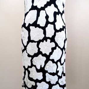 May include: A black and white sequined dress with a cow print pattern. The dress is sleeveless and has a fitted silhouette.