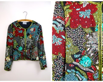 May include: A black sequined jacket with a colourful floral pattern. The jacket has a zip closure and long sleeves. The floral pattern is made up of red, green, blue, and silver sequins.