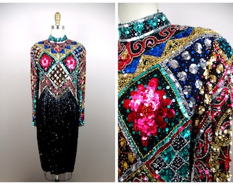 May include: A black sequined dress with a high neck and long sleeves. The dress is decorated with colourful geometric patterns and sequins in shades of pink, red, blue, green, gold, and silver.
