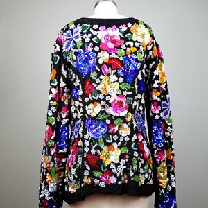 Pode incluir: Um su&eacute;ter preto de manga comprida com um padr&atilde;o floral feito de lantejoulas. As lantejoulas s&atilde;o de v&aacute;rias cores, incluindo rosa, azul, verde, amarelo e laranja.
