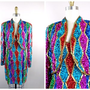 May include: A sequined dress and jacket set in a geometric pattern of red, blue, green, pink, and gold. The dress and jacket are both sleeveless and have a V-neck.