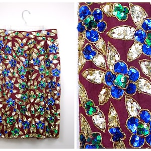Puede incluir: Una falda color burdeos con un estampado floral hecho de lentejuelas doradas, azules y verdes.