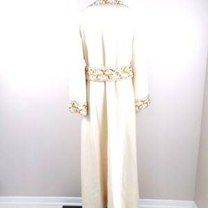May include: A long, white robe with gold and white beading around the neckline, cuffs, and waist.