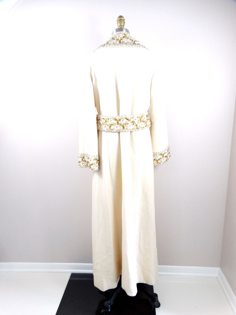 May include: A long, white robe with gold and white beading around the neckline, cuffs, and waist.