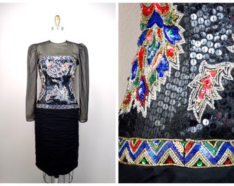 May include: A black sequined dress with a colourful embroidered bodice and a black skirt. The bodice features a geometric pattern with red, blue, green, and gold accents. The skirt is pleated and has a black waistband.