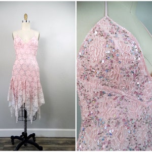 Pode incluir: Um vestido rosa de alças com lantejoulas e contas, com uma sobreposição de renda e uma bainha alta-baixa.