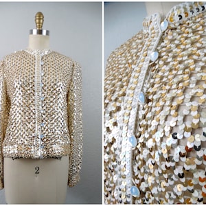 May include: A gold and white sequined jacket with a button-up front. The jacket is made of small, round sequins that are sewn together in a pattern. The jacket has long sleeves and a collar.