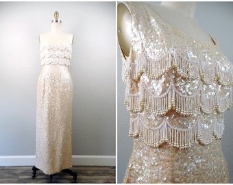 May include: A long, sleeveless, sequined dress with a cream-colored bodice and skirt. The bodice features three rows of beaded fringe.