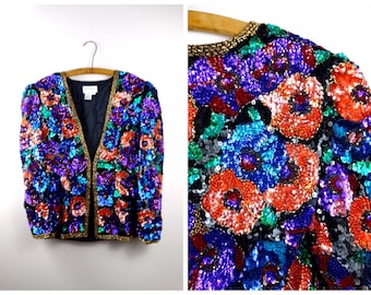 May include: A sequined jacket with a floral pattern in shades of blue, purple, orange, and green. The jacket has a V-neck and a gold trim.