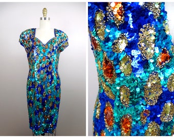 May include: A sequined dress in a blue, teal, gold, and orange pattern. The dress has a fitted silhouette and short sleeves.