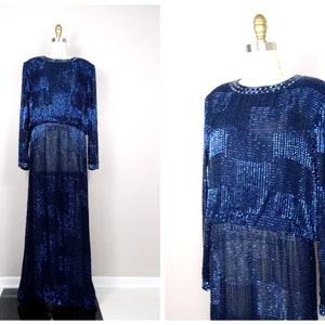 May include: A long, navy blue sequined gown with a geometric pattern. The gown has long sleeves and a round neckline.