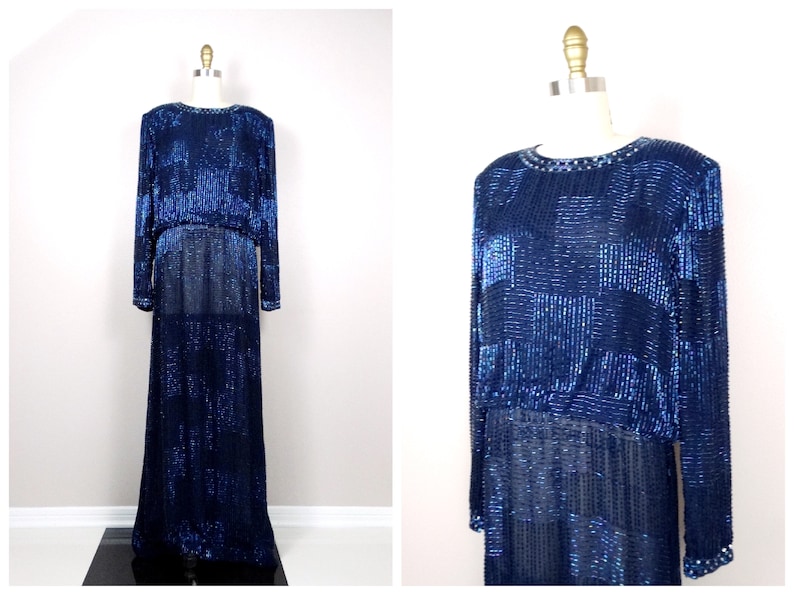 May include: A long, navy blue sequined gown with a geometric pattern. The gown has long sleeves and a round neckline.