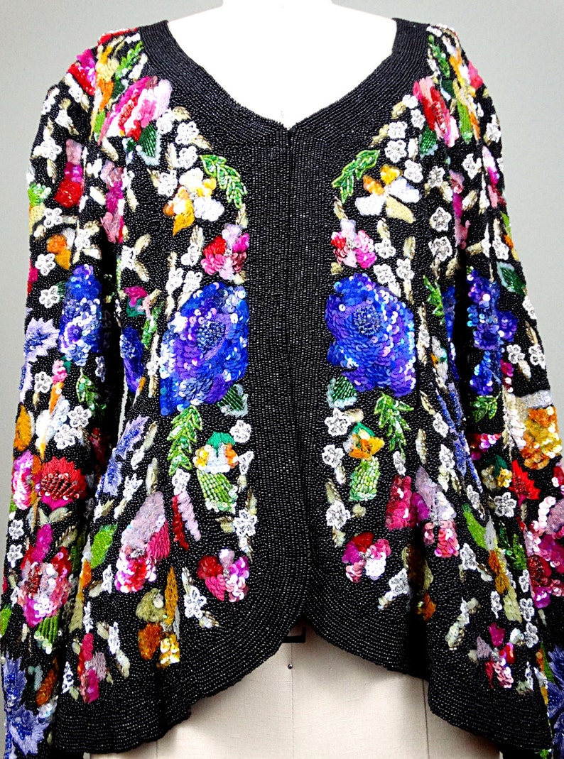 Pode incluir: Uma jaqueta preta de contas com um design floral. A jaqueta &eacute; adornada com lantejoulas e contas coloridas, criando um padr&atilde;o vibrante e intrincado.