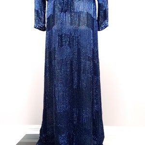 May include: A long, navy blue sequined dress with a geometric pattern. The dress has long sleeves and a fitted bodice.