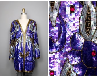 May include: A purple and silver sequined jacket with gold embroidery and pink accents. The jacket has a V-neck and long sleeves.